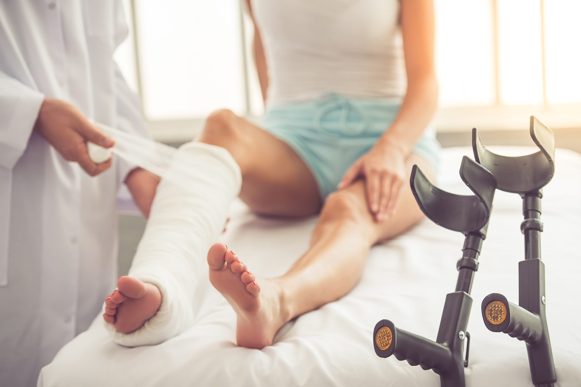 Cropped image of doctor bandaging woman's broken leg