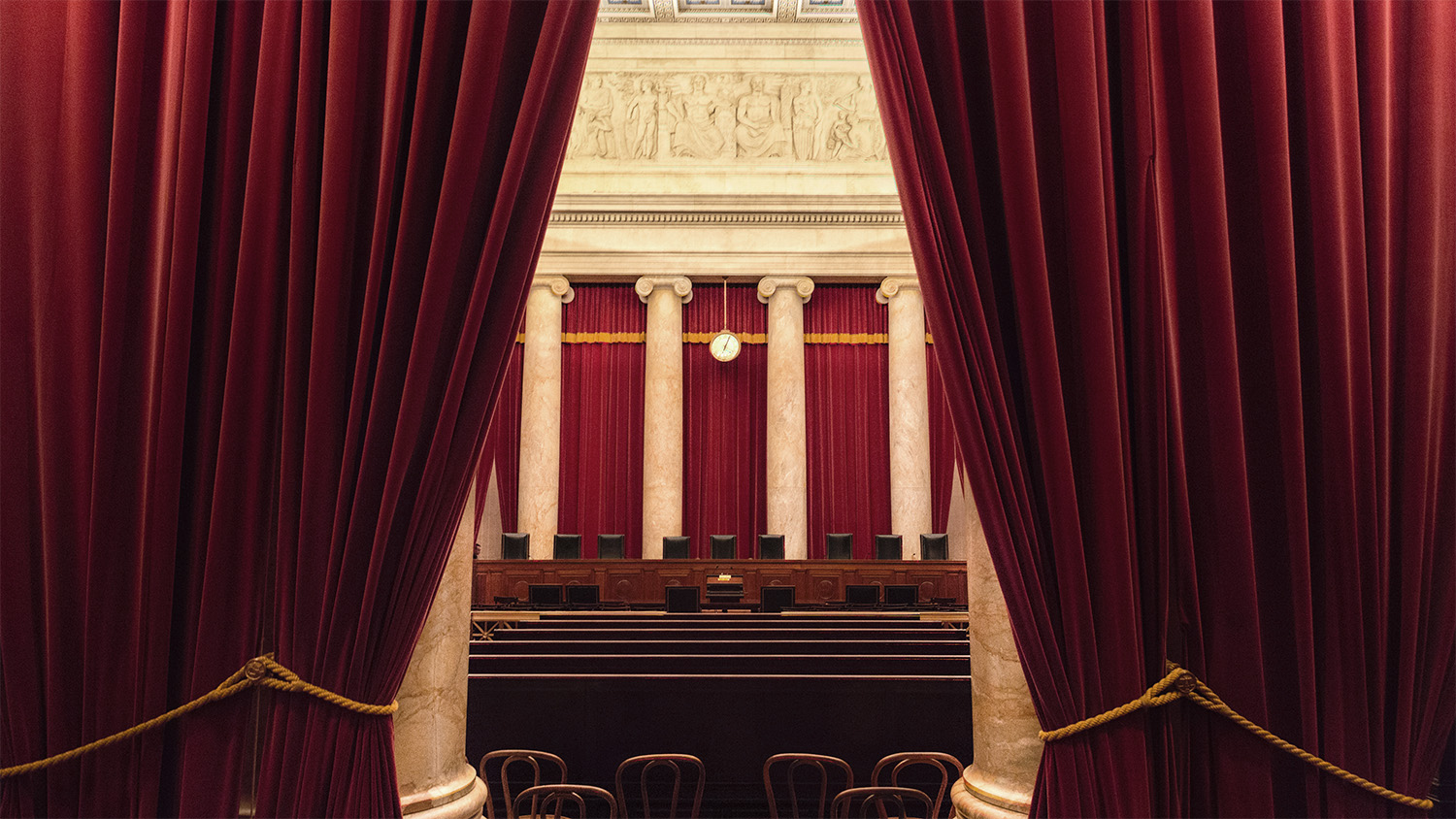 A view of the US Supreme Court Chambers from the back, with curtains mostly drawn.