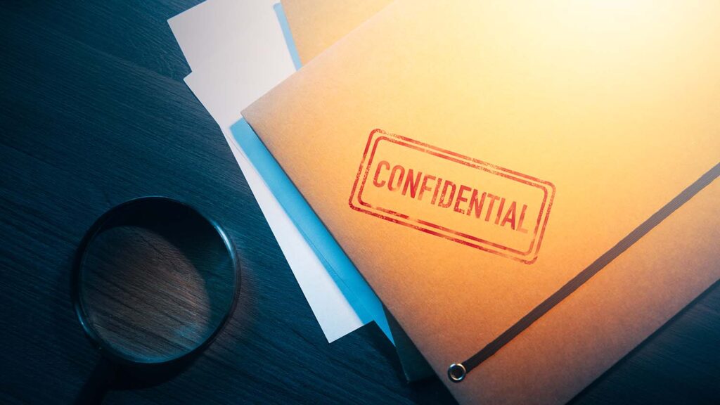 legal document folder with red confidential stamp sitting on a dark colored table