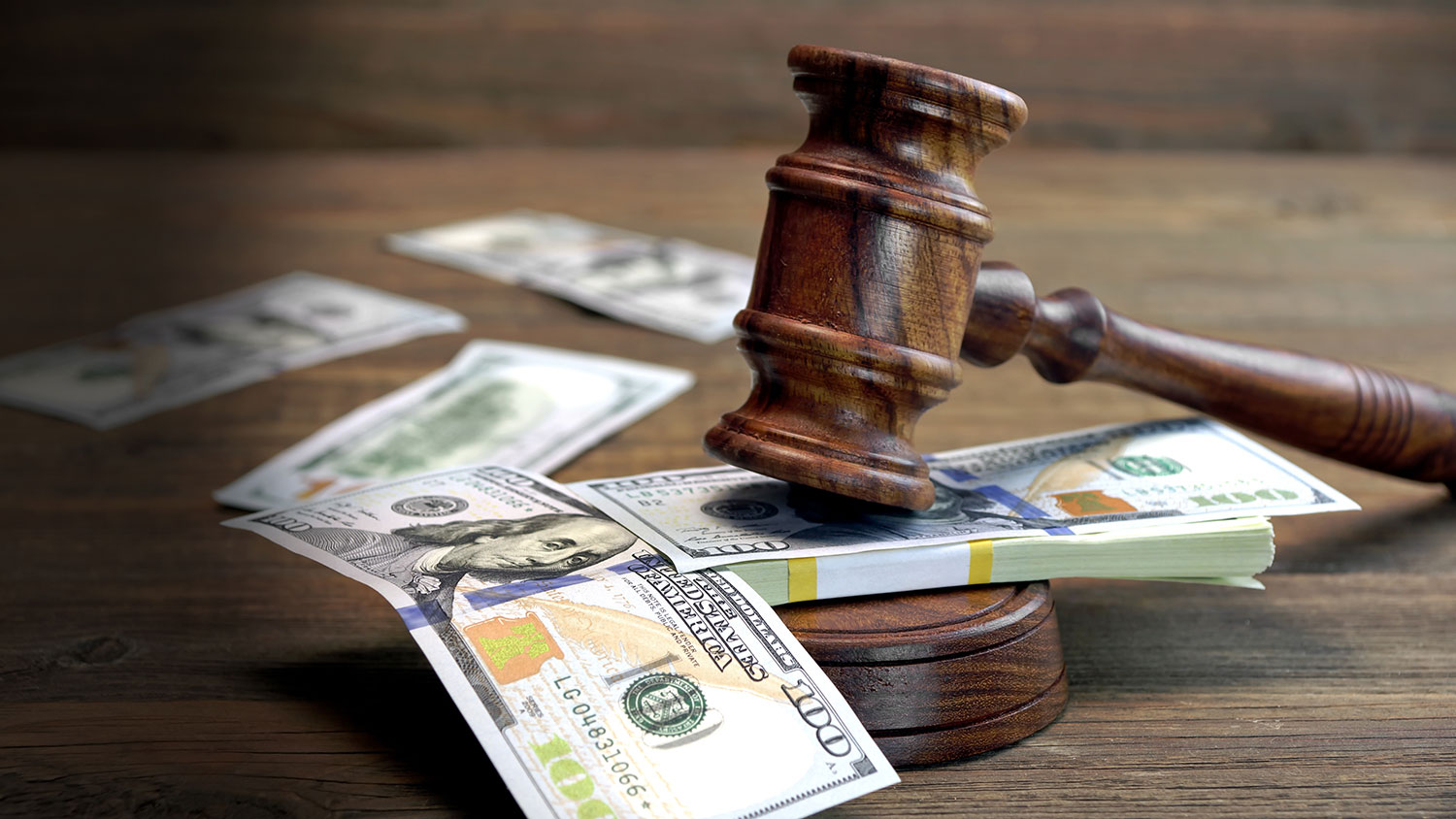 A gavel rests on top of 100 dollar bills